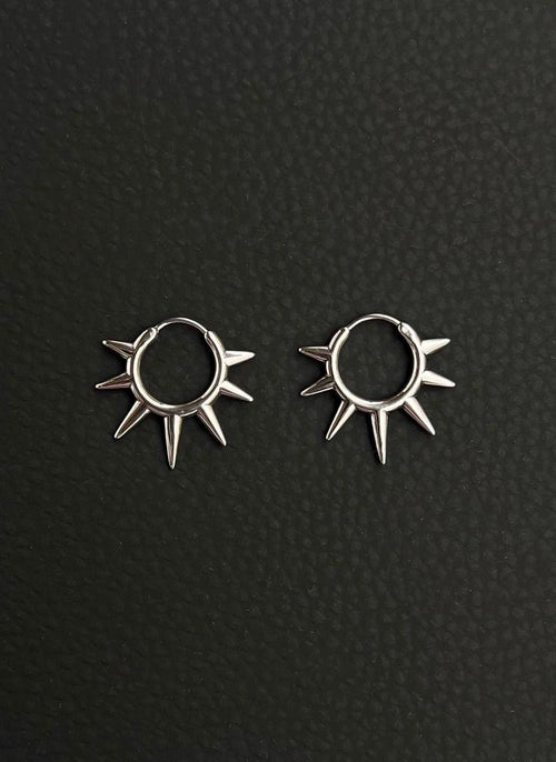 A pair of silver hoop earrings with a sunburst design. Each earring has a circular hoop with multiple pointed spikes radiating outwards. Handmade stainless steel earrings with a geometric sun design.