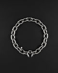 A stainless steel silver chunky heavy thick industrial chain necklace. The necklace has two pointed spikes at the clasp, the clasp is a piercing barbel. The jewellery is displayed on a black surface.