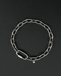 A handmade silver industrial chain necklace with large rectangular links. The necklace is made of stainless steel. The necklace is made from thick 4mm chain. The necklace includes a quick link carabiner and a smiley pendant. queer aesthetics