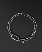 A handmade silver industrial chain necklace with large rectangular links. The necklace is made of stainless steel. The necklace is made from thick 4mm chain. The necklace includes a quick link carabiner and a smiley pendant. queer aesthetics