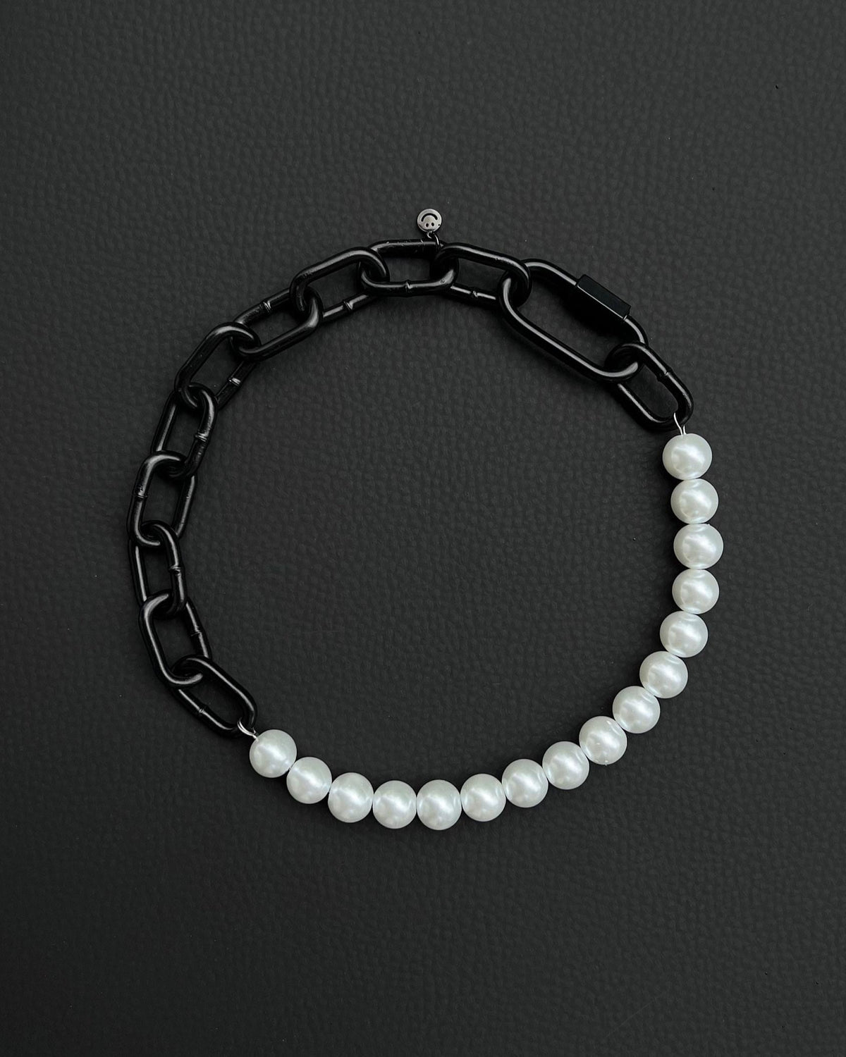 A handmade black industrial chain necklace with large, chunky, rectangular links. The necklace is made of metal steel. The necklace is made half-half from thick 4mm chain and 12mm glass white pearl beads. The necklace includes a black quick link carabiner and a smiley pendant.