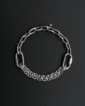 Handmade stainless steel martingale chain choker with two industrial chain types, two quick link clasps and a small smiley charm. Silver finish necklace photographed on a black background.