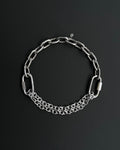 Handmade stainless steel martingale chain choker with two industrial chain types, two quick link clasps and a small smiley charm. Silver finish necklace photographed on a black background.
