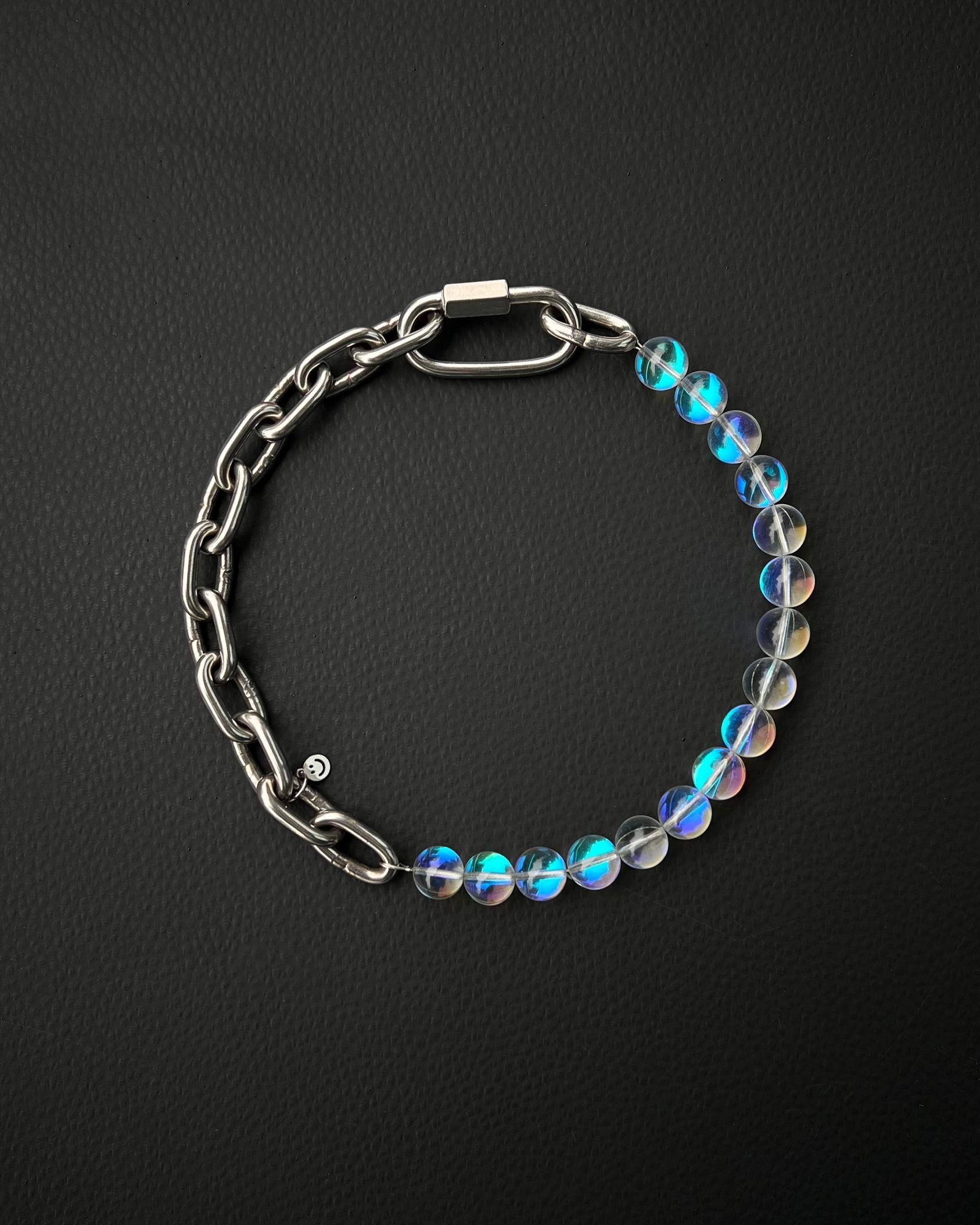 A handmade silver industrial chain necklace with large, rectangular links.
The necklace is made of stainless steel. The necklace is made half-half from thick 4mm chain and 12mm iridescent clear beads.The necklace includes a quick link carabiner and a smiley pendant.