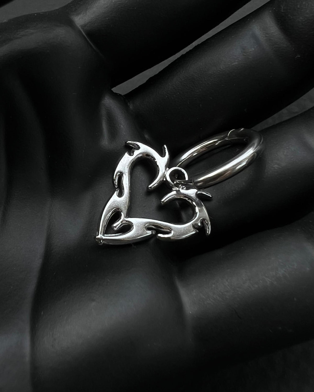 a stainless steel hoop earring with a cyber silgilism heart pendant