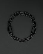 Handmade  steel martingale chain choker with two industrial chain types, two quick link clasps and a small smiley charm. Black finish necklace photographed on a black background.