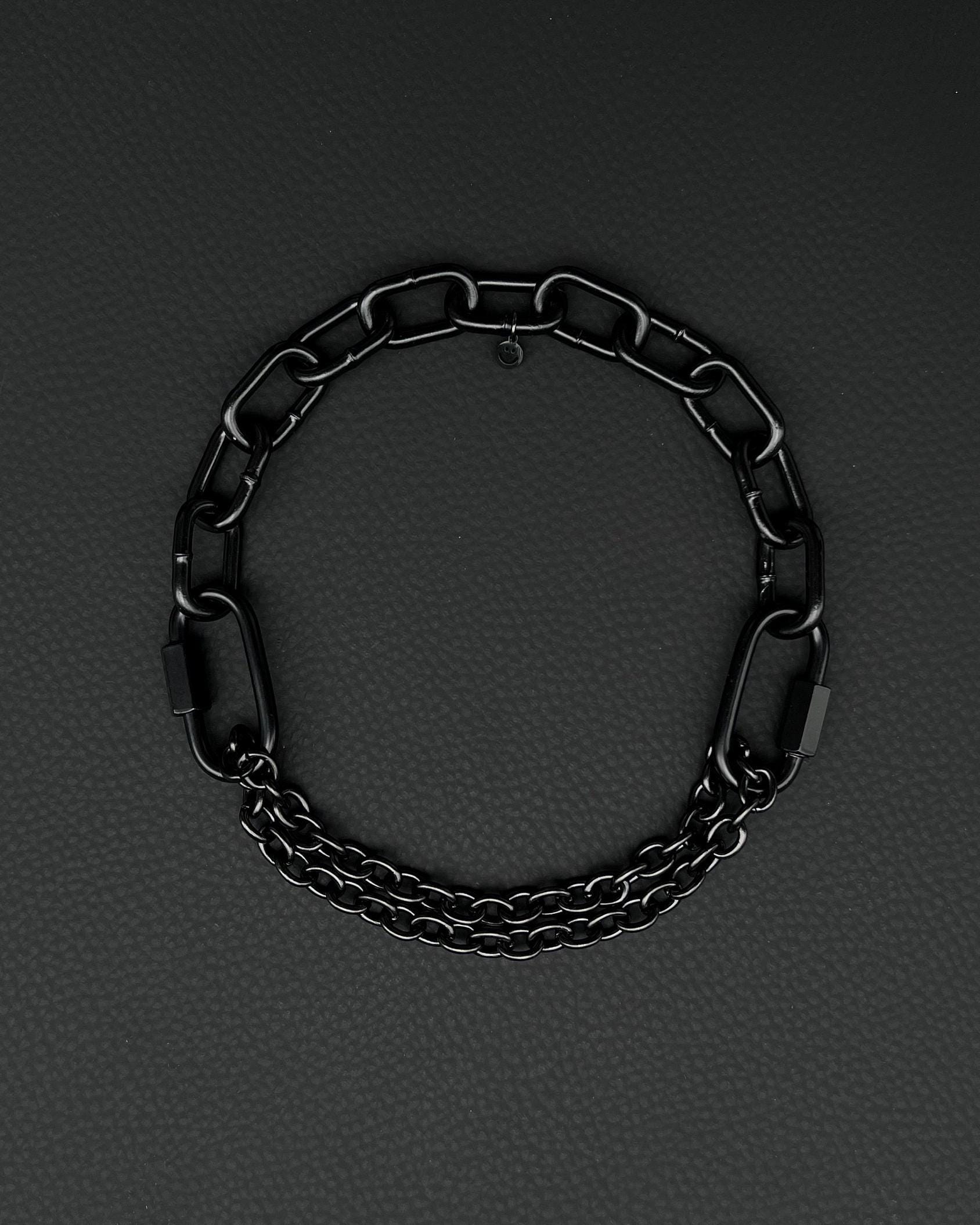 Handmade  steel martingale chain choker with two industrial chain types, two quick link clasps and a small smiley charm. Black finish necklace photographed on a black background.