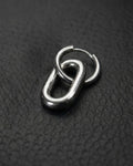 A single silver stainless steel metal earring with a distinctive design. It features a small hoop linked to a larger, elongated oval. The metal has a polished, reflective surface. The earring is set against a dark background.