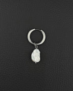 A silver-coloured stainless steel metal hoop earring featuring a single, irregular, white baroque pearl charm suspended from the bottom. The hoop has a smooth, polished finish and a hinged closure mechanism, while the pearl displays a textured surface.