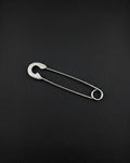 A silver-coloured stainless steel safety pin earring featuring a classic U-shaped coil at one end and a protective clasp mechanism at the other. The pin is constructed from a single piece of wire, showcasing a smooth, polished finish and a functional design.