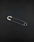 A silver stainless steel blunt safety pin earring featuring a classic U-shaped coil at one end and a protective clasp mechanism at the other. The pin is constructed from a single piece of wire, showcasing a smooth, polished finish and a functional design.