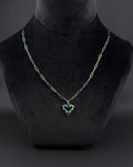 An iridescent oil-slick coloured, rainbow, stainless steel necklace featuring a paperclip style chain and a central heart-shaped pendant. The metal finish displays shifting hues of blue, green, and purple across the entire surface of the chain and the heart charm.