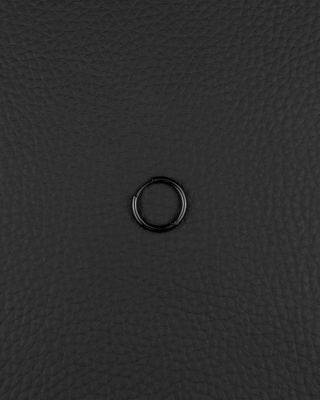 A single, stainless steel circular hoop earring in black finish. The earring features a thin, continuous metal band with a small hinged closure mechanism visible on one side, creating a simple and uniform ring shape for ear piercing.