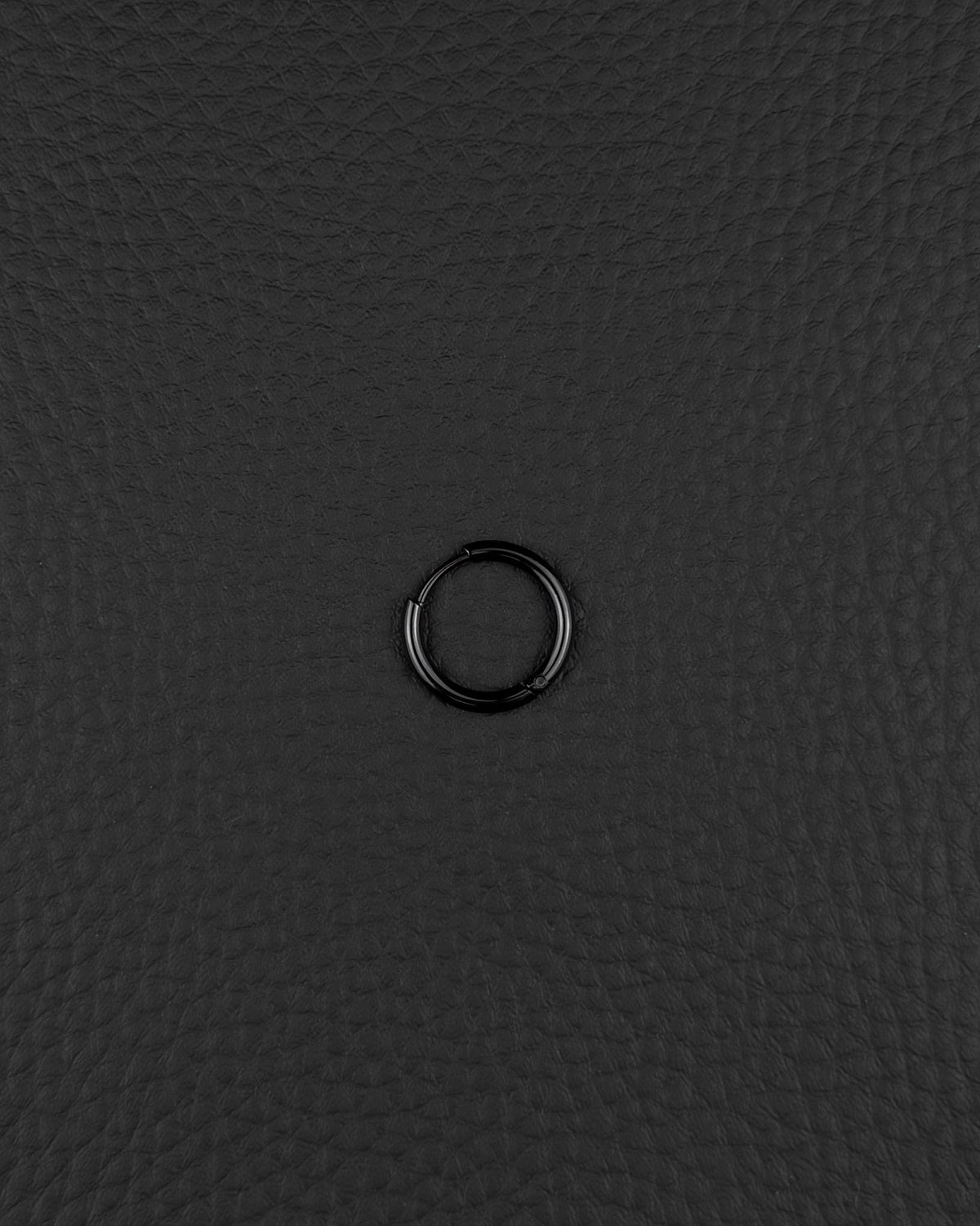 A single, stainless steel circular hoop earring in black finish. The earring features a thin, continuous metal band with a small hinged closure mechanism visible on one side, creating a simple and uniform ring shape for ear piercing.