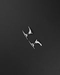 A silver-toned stainless steel ear cuff featuring two distinct, smooth, pointed, and curved metal spikes. The larger, elongated spike rests along the upper outer edge of the ear, while the smaller, tapered spike sits below the earlobe, creating a sleek look.